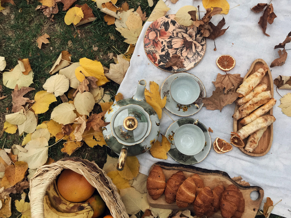 cozy autumn picnic with plaid blanket, thermos of coffee and seasonal fruits on a grassy field